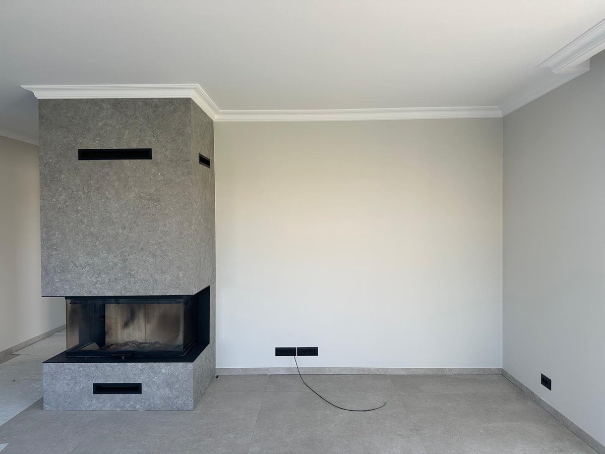 Empty modern living room with fireplace insert, concrete floor, white walls, and ceiling with crown molding