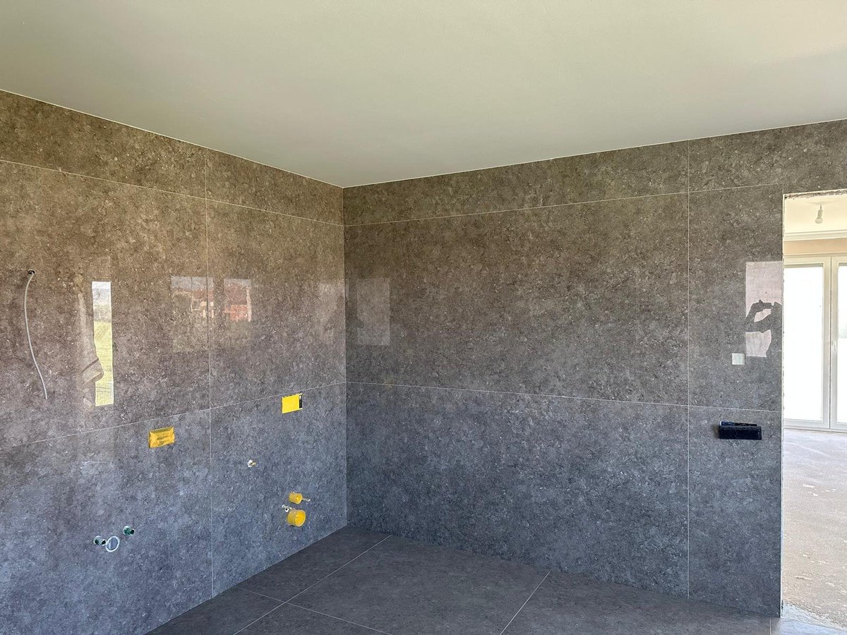 Empty room under construction with concrete walls, yellow electrical outlet boxes, and open doorway